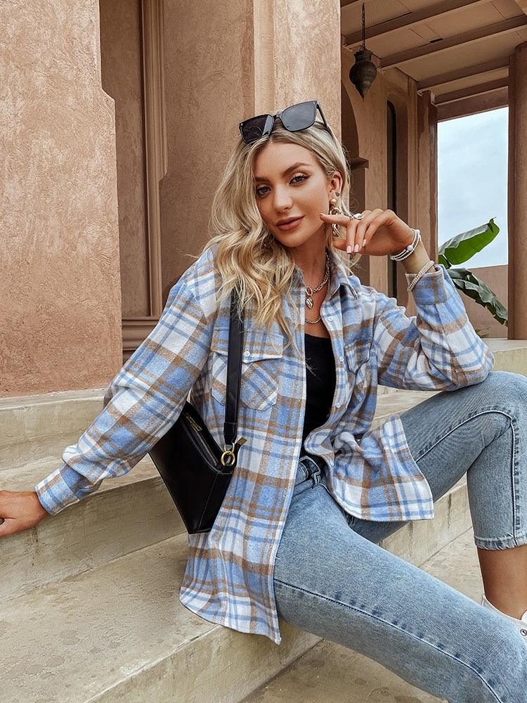 Frau in kariertem Hemd, Jeans und Sonnenbrille, sitzt auf Treppe, modisches Outfit, lässiger Stil.