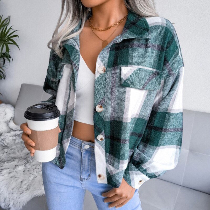 Frau in grün-karierter Flanelljacke, weißem Top, Jeans, hält Kaffeebecher, modisch, lässig.