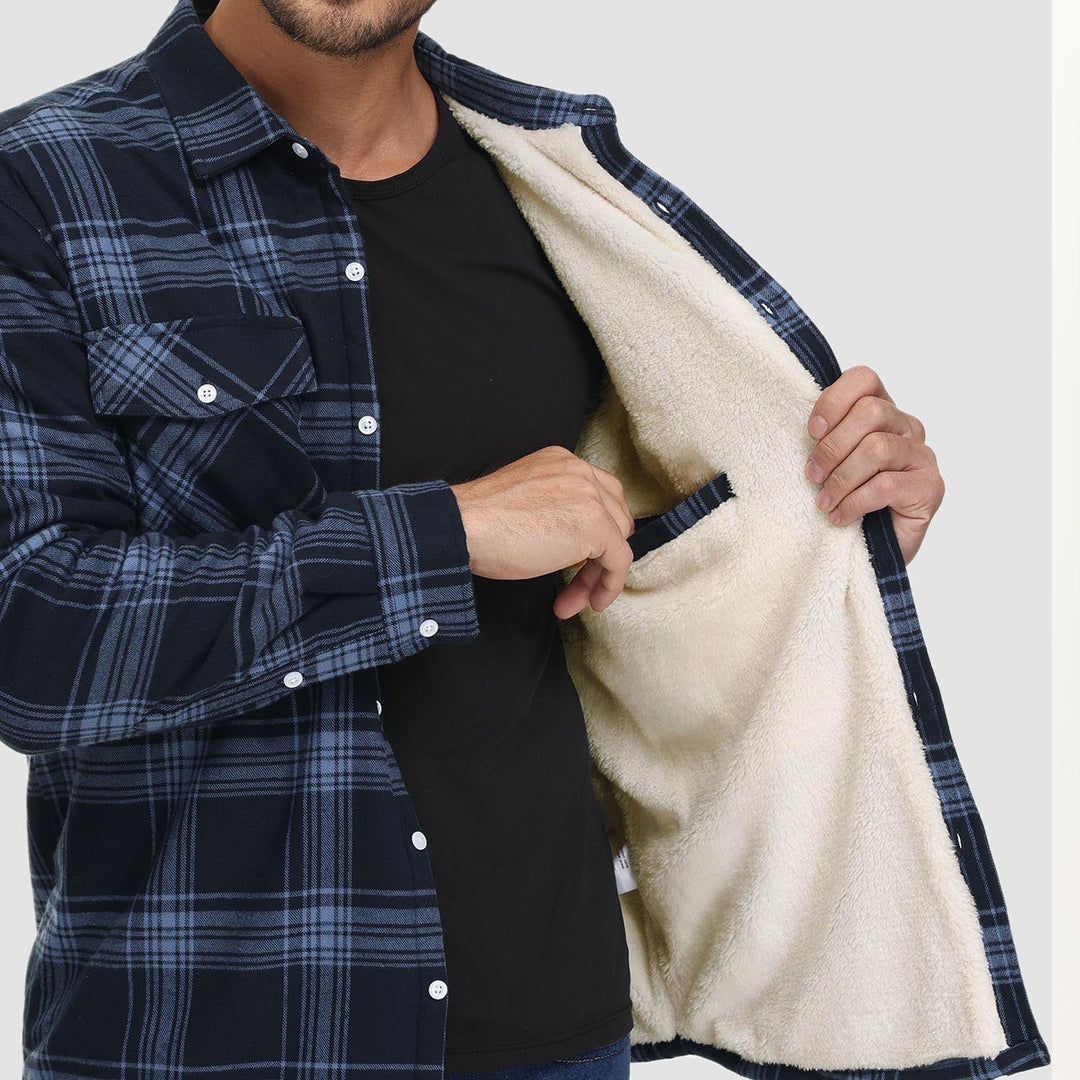 Mann zeigt blau kariertes Flanellhemd mit Fleece-Innenfutter und Brusttasche.