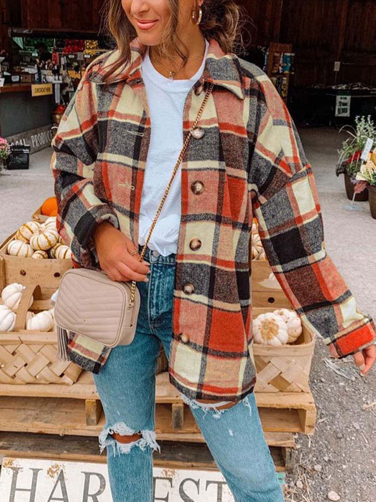 Frau in karierter Wolljacke, Jeans, beiger Umhängetasche, Herbstmode, Kürbisse im Hintergrund.