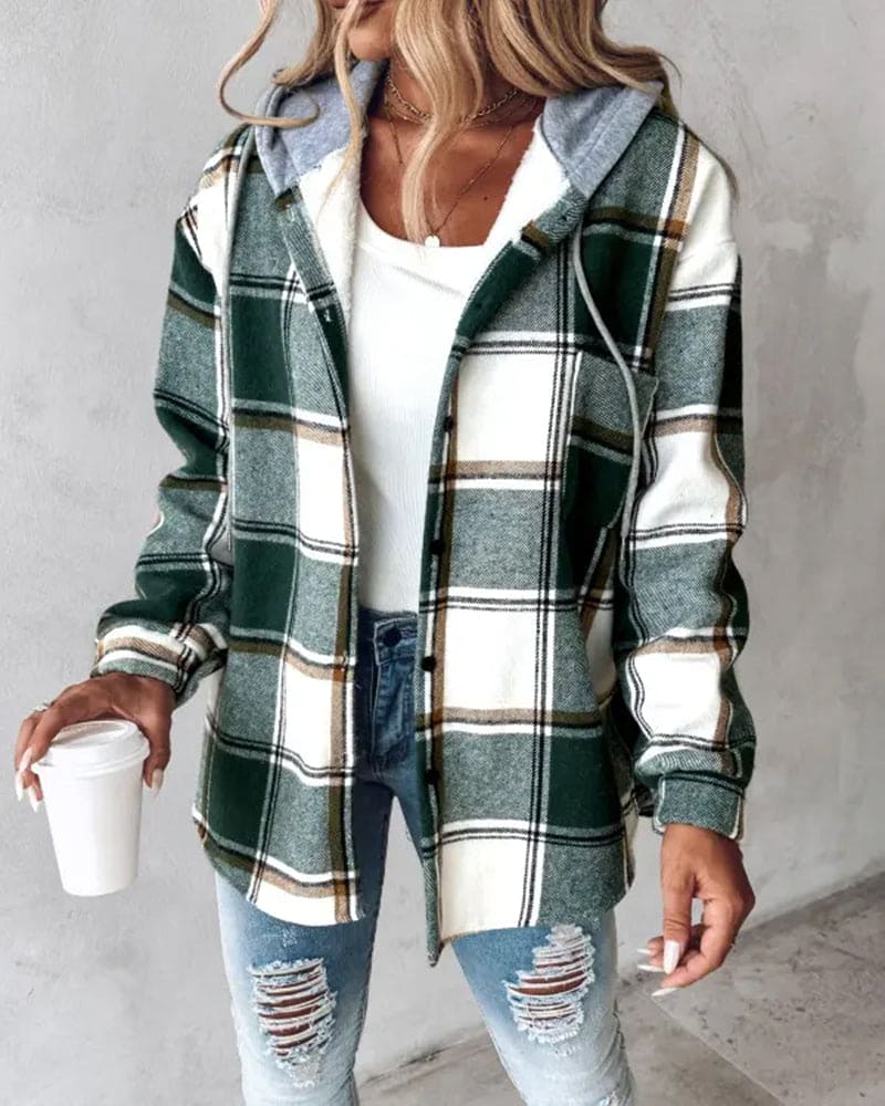 Frau in grün-weiß karierter Jacke, zerrissene Jeans, hält Kaffeebecher, modischer Herbstlook.
