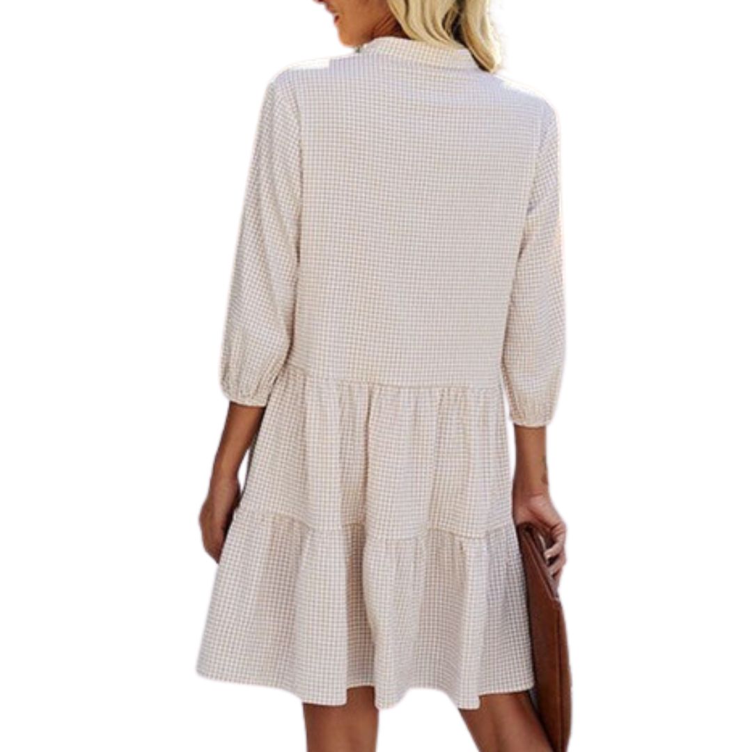 Frau in kariertem, weißem Sommerkleid mit Dreiviertelärmeln von hinten.