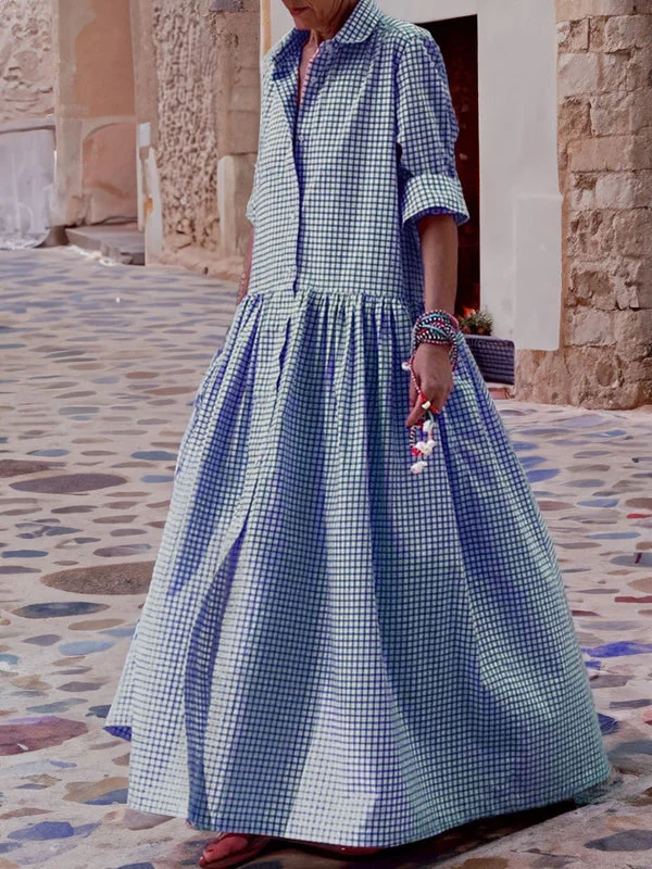 Frau in blau-weiß kariertem Maxikleid auf gepflastertem Weg, Sommermode, lässiger Stil.