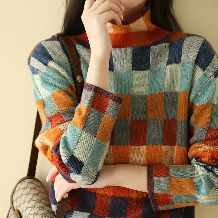 Frau in buntem kariertem Pullover aus Wolle, hält Designer-Handtasche, Herbstmode-Trend.