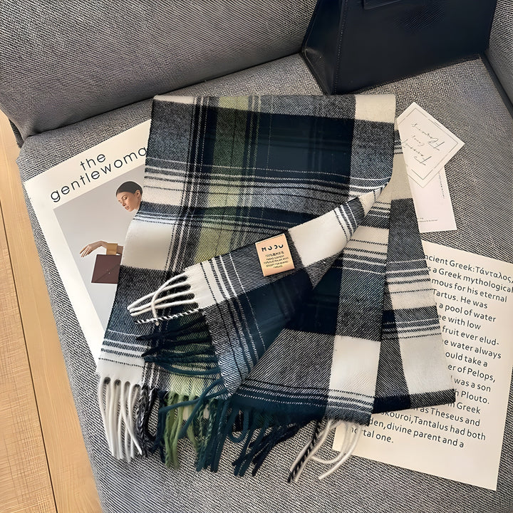 Kariertes Wollschal in Grün und Weiß auf grauem Sofa, modisches Accessoire, Herbst-Winter.