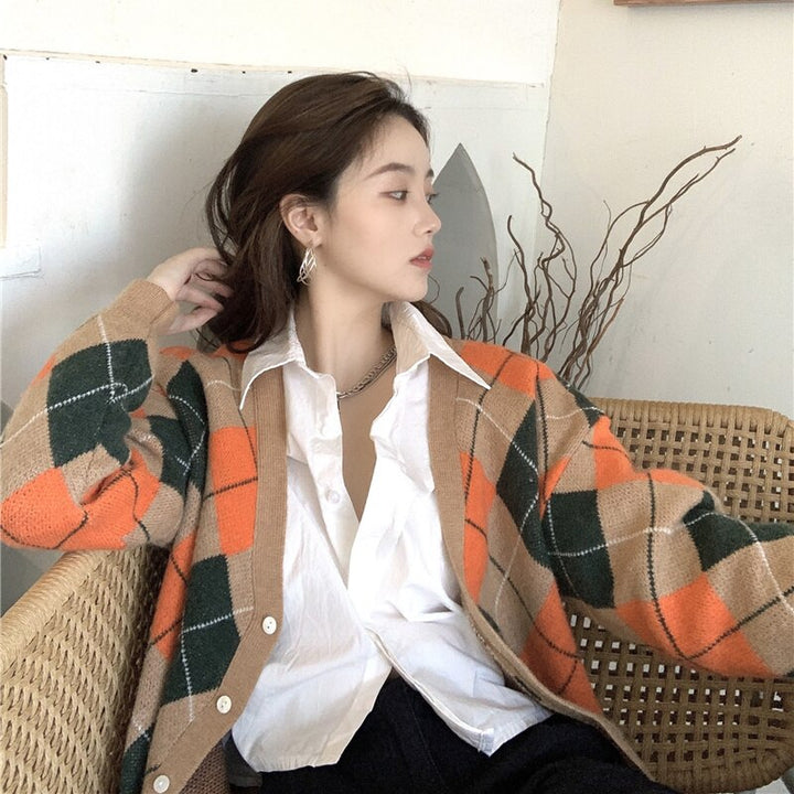 Frau in kariertem Strickcardigan, weißer Bluse, sitzt auf Rattanstuhl, modisch, Herbstlook.