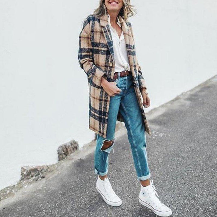 Frau in kariertem Mantel, weiße Bluse, zerrissene Jeans, weiße Sneaker, lässiger Streetstyle.