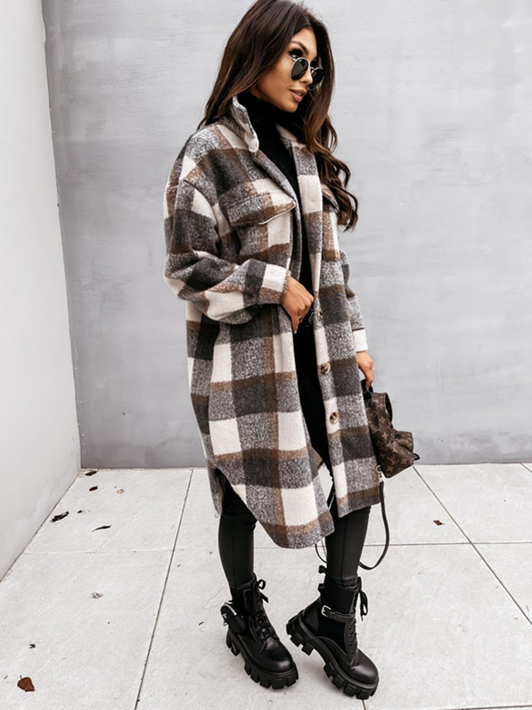 Frau in kariertem Oversize-Mantel, schwarze Stiefel, Sonnenbrille, modischer Herbstlook.