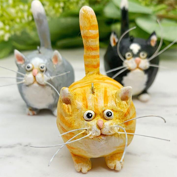 Drei handgefertigte Katzenfiguren aus Keramik, bunt bemalt, auf weißem Hintergrund.