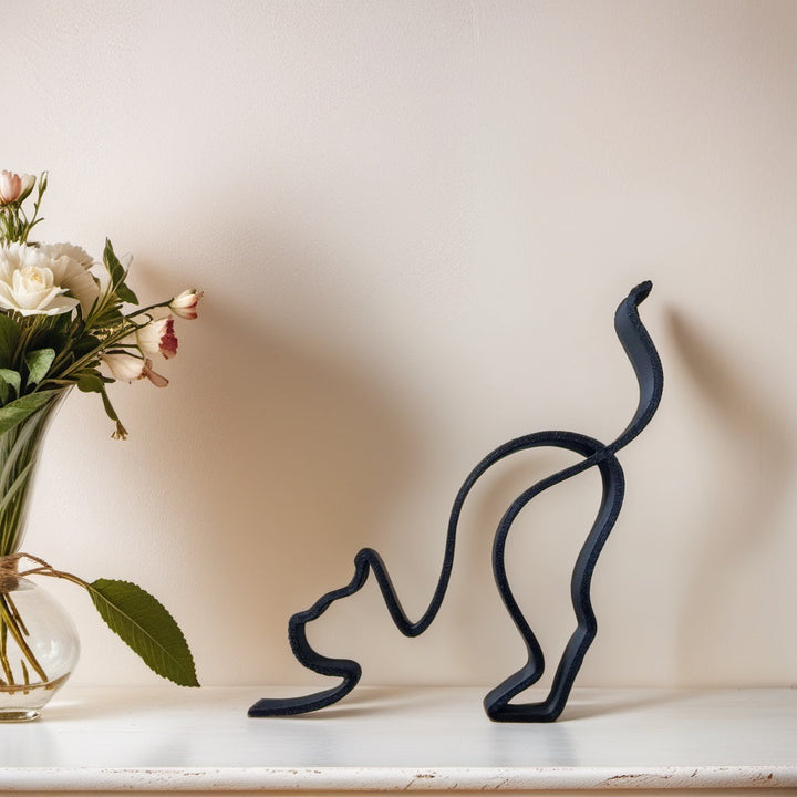 Schwarze Katzen-Skulptur aus Metall auf Regal, neben Vase mit Blumen, moderne Dekoration.