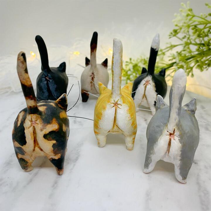 Sechs handgefertigte Katzenfiguren aus Keramik, bunt bemalt, auf weißem Hintergrund.