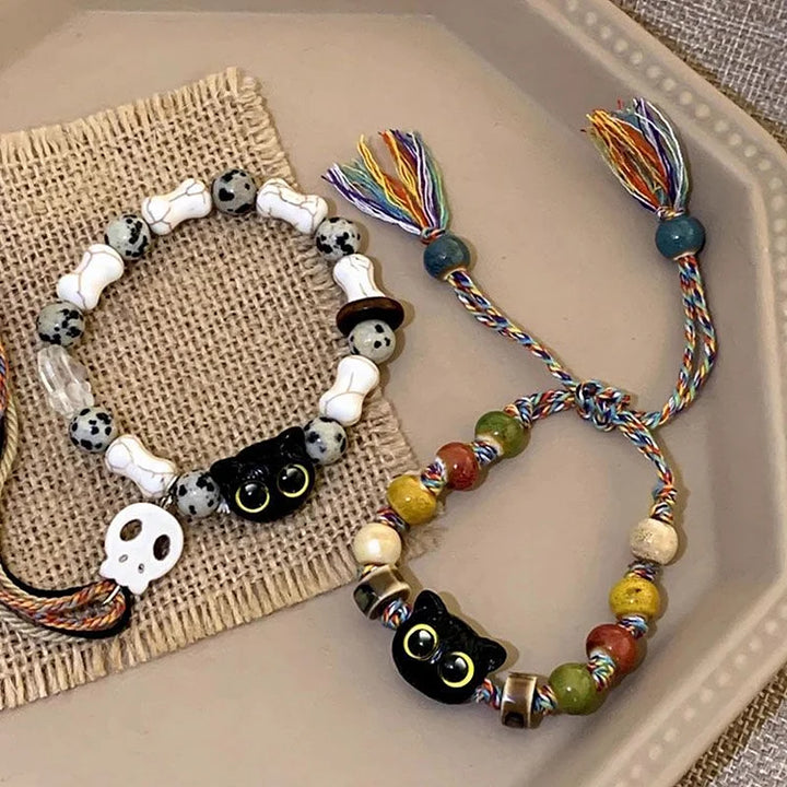 Zwei Armbänder mit Katzen- und Totenkopf-Designs, bunte Perlen, handgefertigt, auf Tablett.