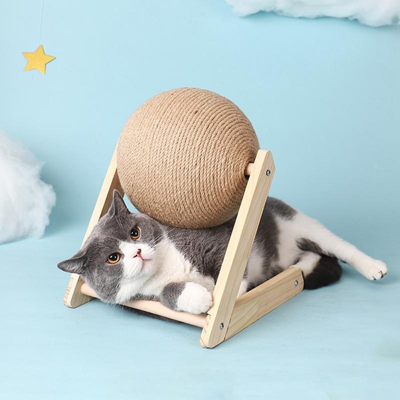 Graue Katze mit Kratzball aus Sisal auf Holzgestell, Spielzeug für Katzen, blauem Hintergrund.