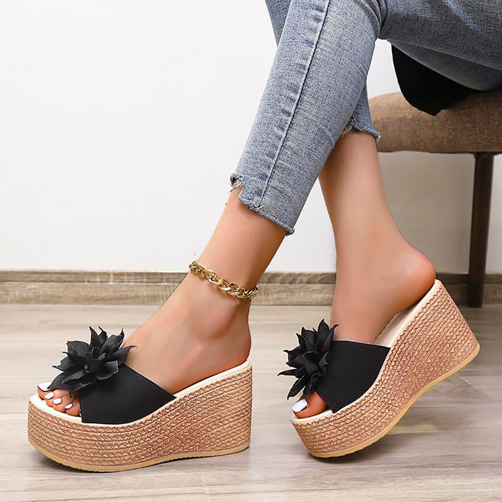 Schwarze Plateau-Sandalen mit Blumen, Damen, Keilabsatz, Sommermode, Jeanshintergrund.