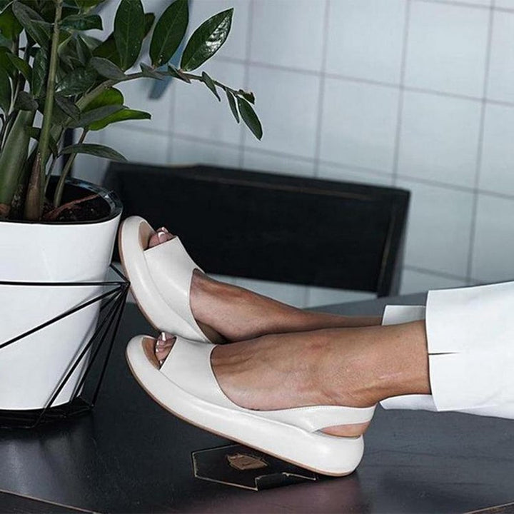 Weiße Damen-Sommersandalen, bequem, modern, auf Tisch neben Pflanze.