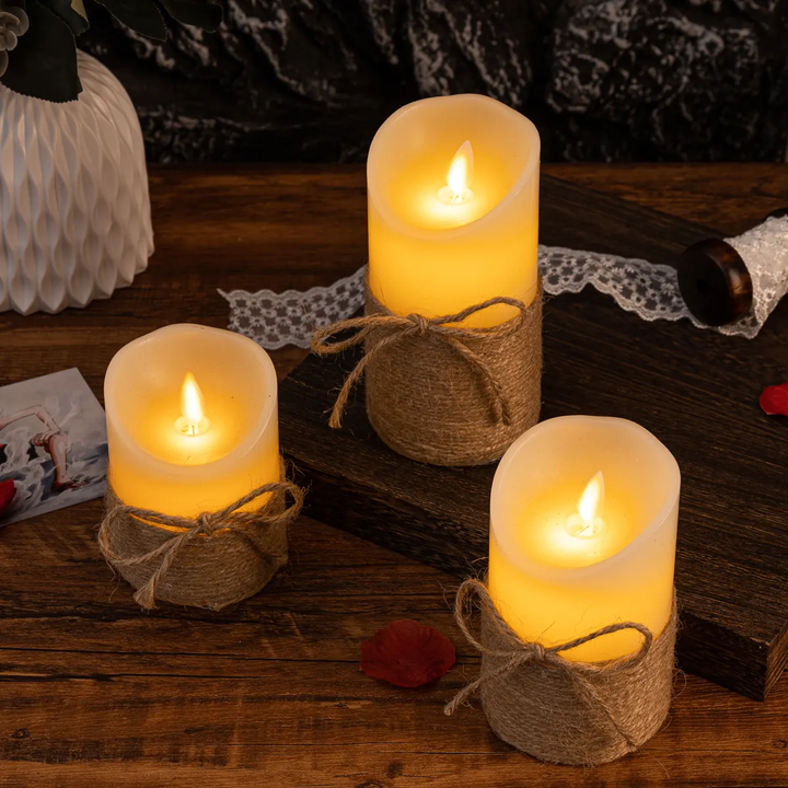 Drei LED-Kerzen mit Flammeneffekt, umwickelt mit Juteband, auf Holztisch, dekorativ.