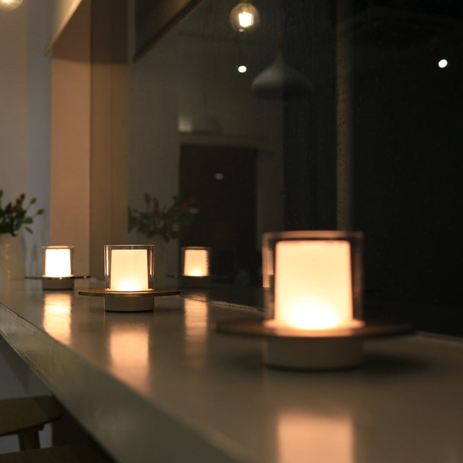 Moderne LED-Kerzen auf Fensterbank, warmweißes Licht, gemütliche Dekoration, Nachtansicht.