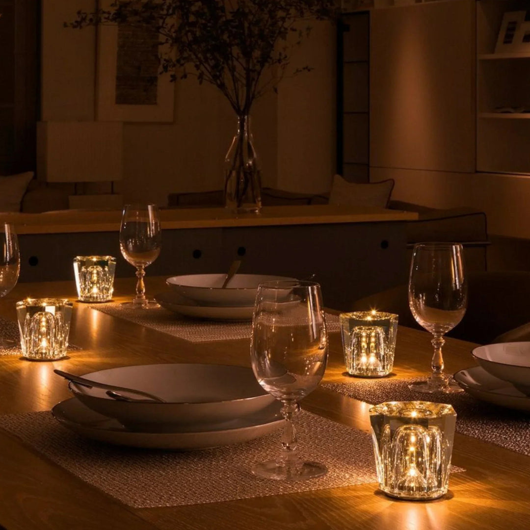 Kerzenhalter aus Kristallglas mit warmem LED-Licht auf einem gedeckten Tisch.