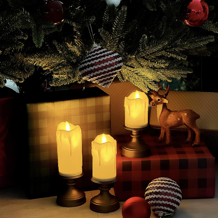 Drei LED-Kerzen unter Weihnachtsbaum, dekoriert mit Geschenken und Rentierfigur.