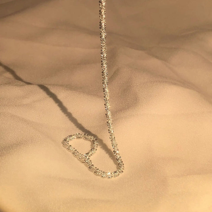 Goldene Halskette mit funkelnden Diamanten auf beigem Stoff, eleganter Schmuck für Damen.