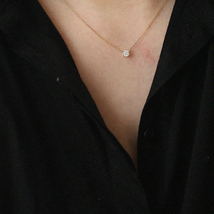 Goldene Halskette mit Diamantanhänger auf schwarzem Hintergrund, eleganter Schmuck für Damen.