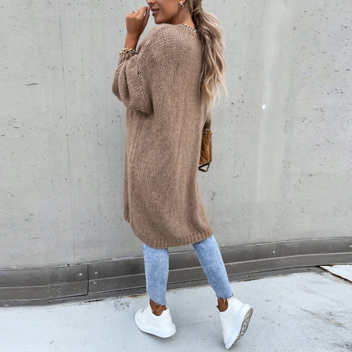 Frau in khaki Strickjacke, blaue Jeans, weiße Sneaker, lässiger Herbstlook, Straßenmode.