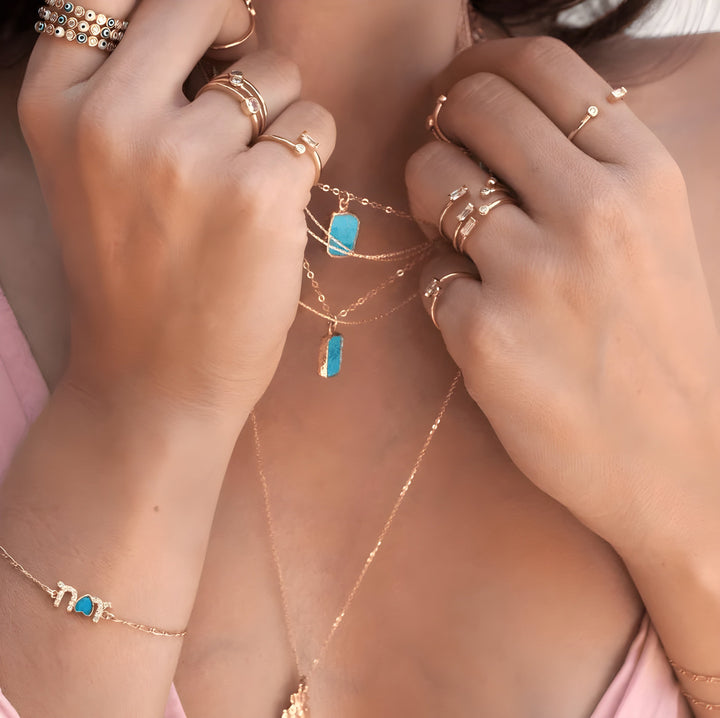 Frau mit türkisfarbener Boho-Halskette, goldene Ringe, handgemacht, modischer Schmuck.