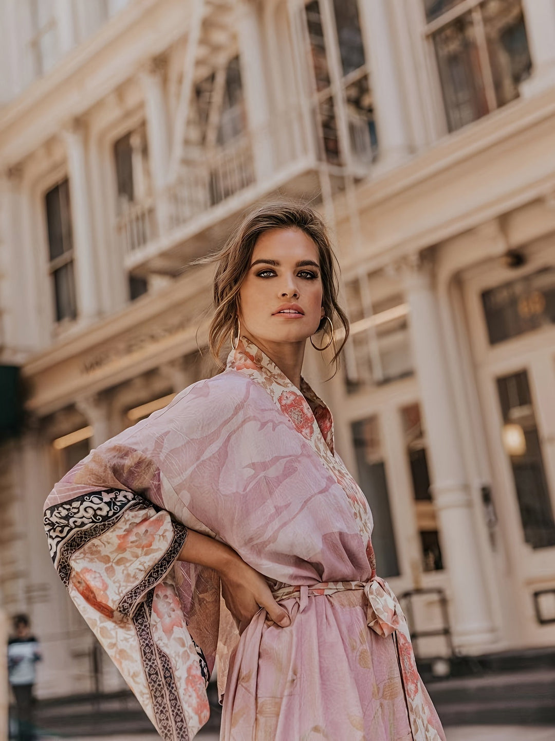 Frau in rosa Kimono mit Blumenmuster vor historischer Architektur, Modefotografie.
