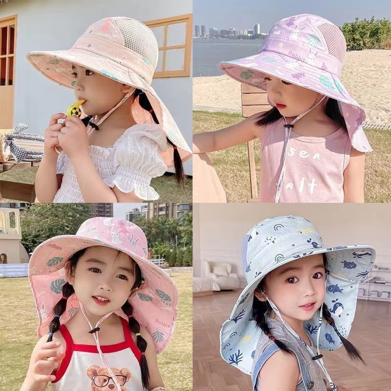 Mädchen mit Sonnenhüten, rosa und blau, Strandhintergrund, Sommermode, Kindermode.
