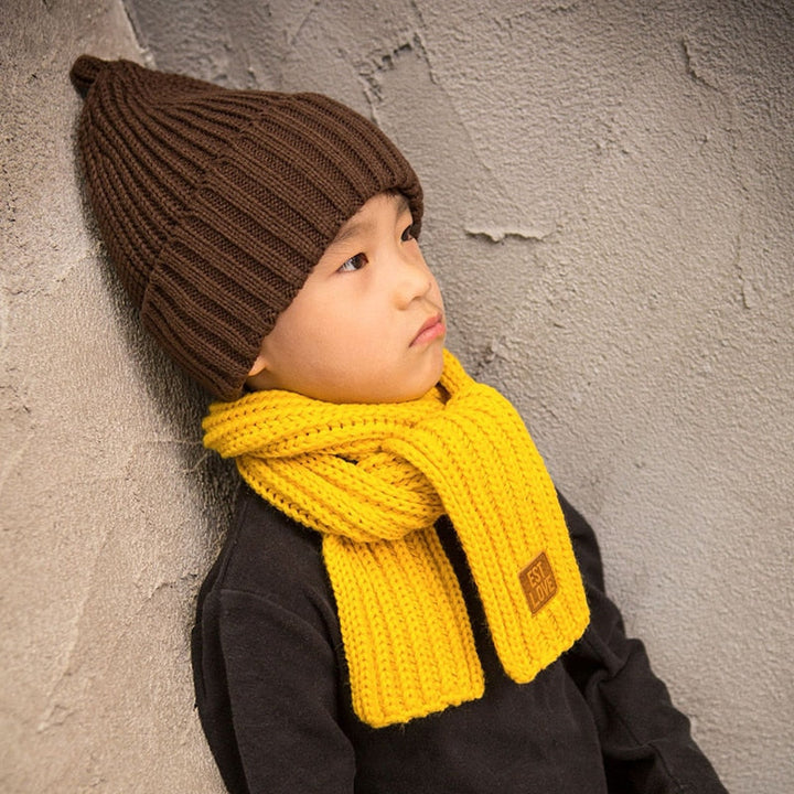 Kind mit brauner Strickmütze und gelbem Schal, Wintermode, warm, bequem, stilvoll.