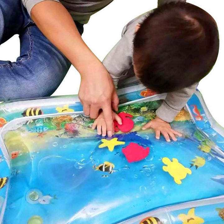 Kleinkind spielt auf blauer aufblasbarer Wasserspielmatte mit bunten Formen, PVC, Indoor-Spielzeug.