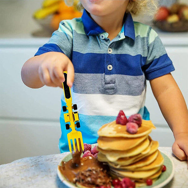Kleinkind mit gestreiftem Hemd isst Pfannkuchen mit gelber Gabel, Frühstück, Kinderbesteck.