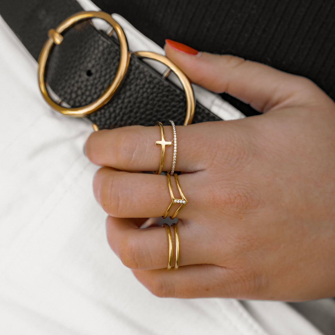 Hand mit goldenen Ringen, Kreuzdesign, minimalistisch, Schmuck, Modeaccessoire, Damenmode.