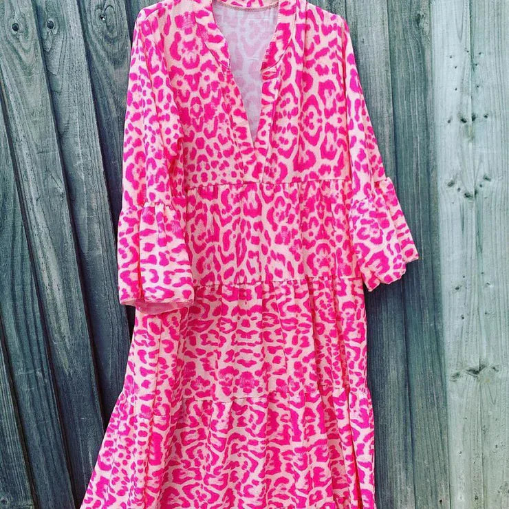 Pinkes Maxikleid mit Leopardenmuster, V-Ausschnitt, langen Ärmeln, Holzlatten-Hintergrund.