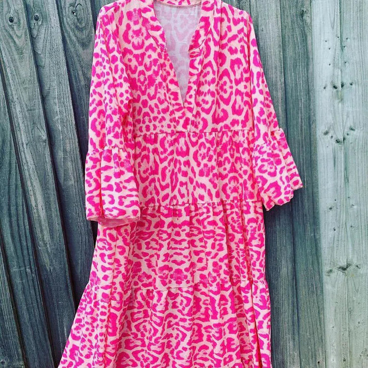 Pinkes Maxikleid mit Leopardenmuster, V-Ausschnitt, langen Ärmeln, Holzlatten-Hintergrund.