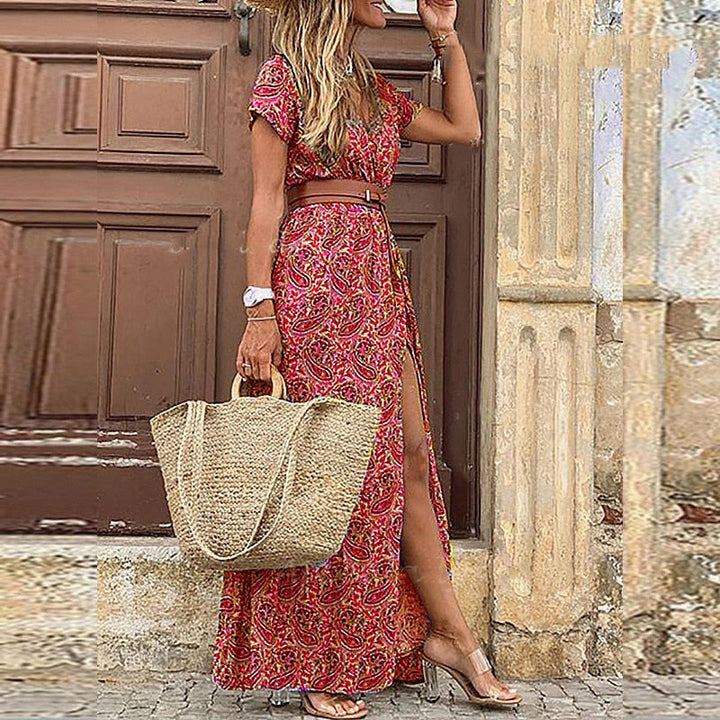 Frau in rotem Maxikleid mit Paisley-Muster, Strohtasche, Sandalen, Sommermode.