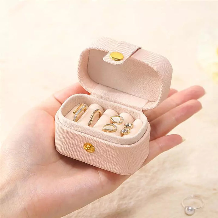 Rosa Schmuckkästchen aus Samt mit Ringen, tragbar, handgehalten, ideal für Reisen.