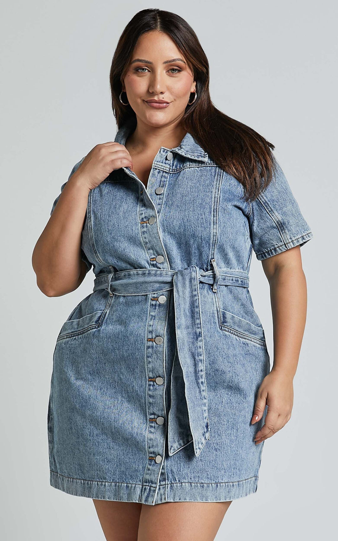 Frau in blauem Jeanskleid mit Knopfleiste und Gürtel, modisches Design, Freizeitkleidung.