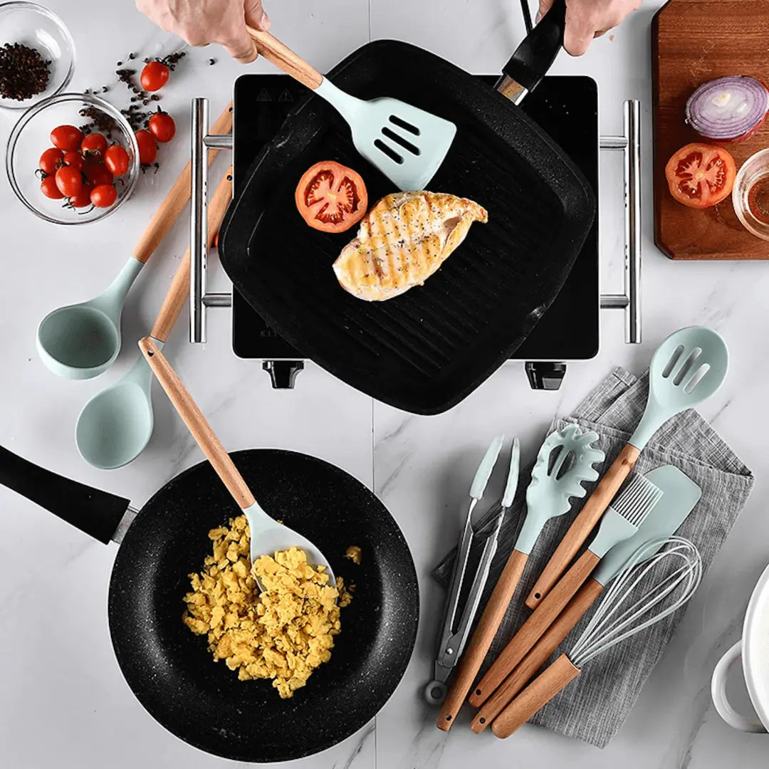 Küchenutensilien Set aus Silikon und Holz, mintgrün, mit Pfanne und Grillpfanne auf Marmoroberfläche.