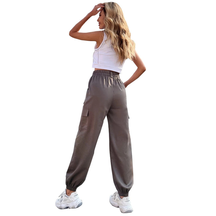 Frau in grauer, hoch taillierter, bequemer Hose und weißem Top, seitlich stehend.