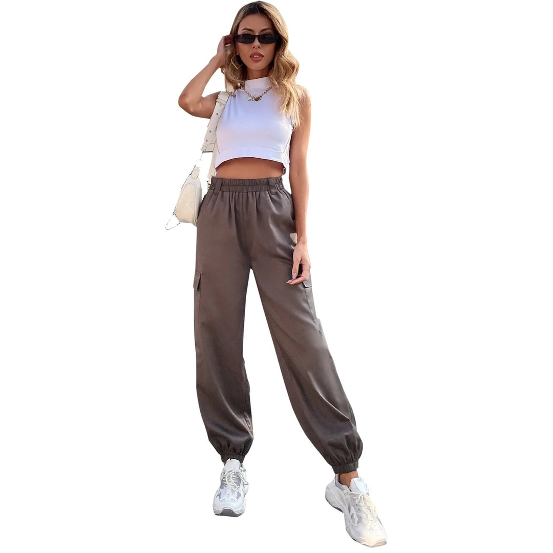 Frau in grauer, hoch taillierter Hose und weißem Top, modisch, lässig, Streetwear-Look.