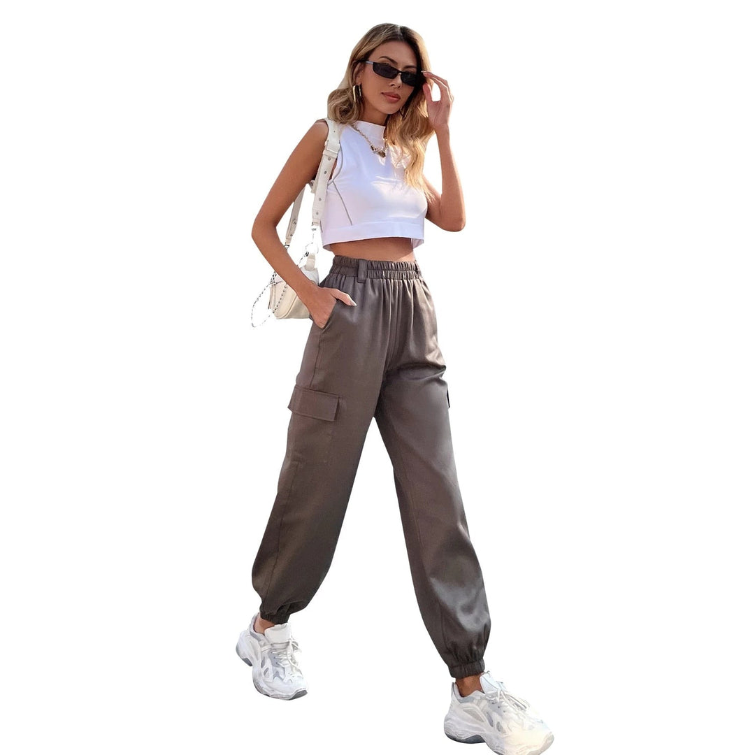 Frau in grauer, hoch taillierter Jogginghose und weißem Crop-Top, modisch, lässig, urban.