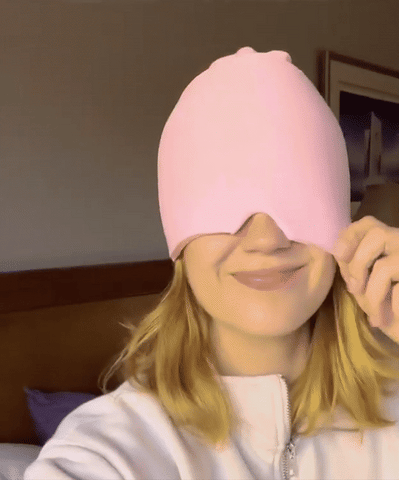 Frau trägt rosa Gel-Kopfschmerz-Kappe, schnelle Linderung, Kompressionstherapie.