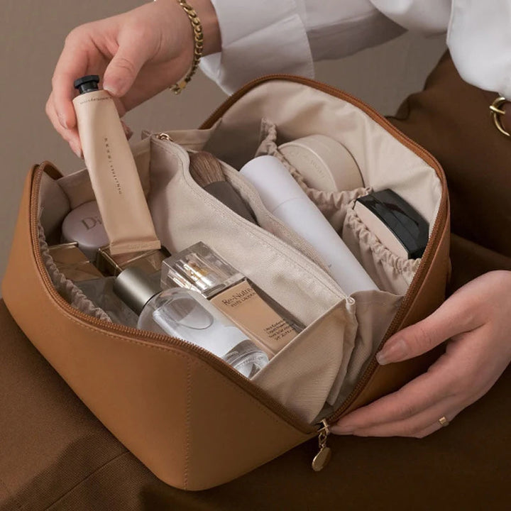 Braune Kosmetiktasche aus Leder, gefüllt mit Make-up-Produkten, ideal für Reisen und Organisation.