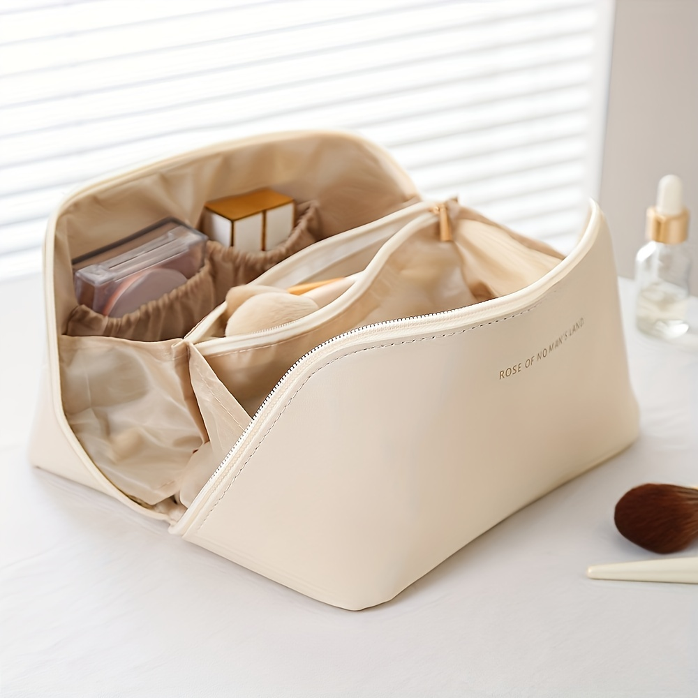 Cremefarbene Kosmetiktasche aus Leder mit Fächern, ideal für Make-up-Aufbewahrung.