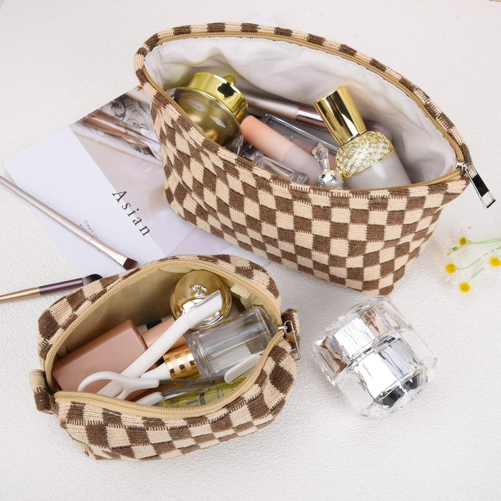 Braune karierte Kosmetiktasche, gefüllt mit Make-up-Produkten, auf weißem Hintergrund.