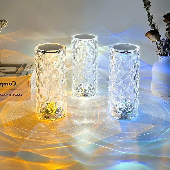Drei LED-Kristalllampen, farbwechselnd, auf Tisch mit Blumen und Buch, moderne Dekoration.