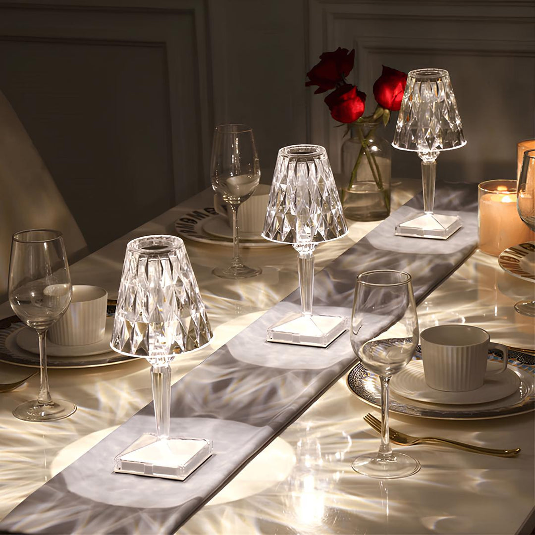 Drei Kristall-Tischlampen auf elegant gedecktem Esstisch mit Weingläsern und Rosen.