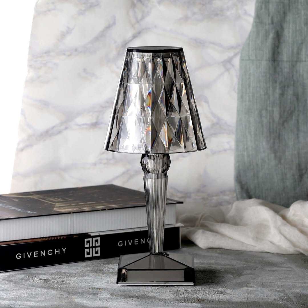 Kristall-Tischlampe auf Bücherstapel, modernes Design, transparent, elegantes Wohnaccessoire.