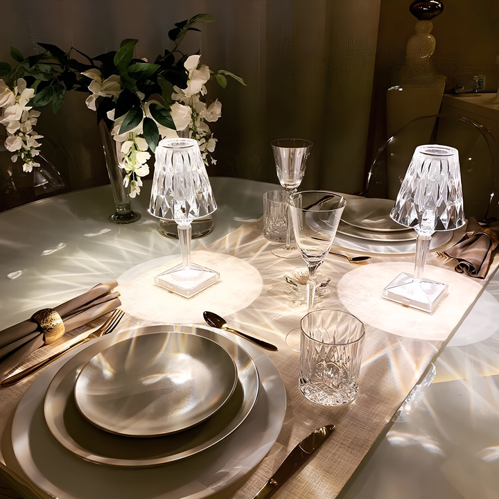 Elegante Tischdekoration mit Kristalllampen, weißen Tellern und Blumenarrangement.